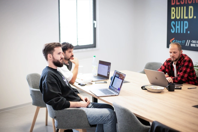Ein Bild von 3 Menschen, die zusammen im Besprechungsraum sitzen